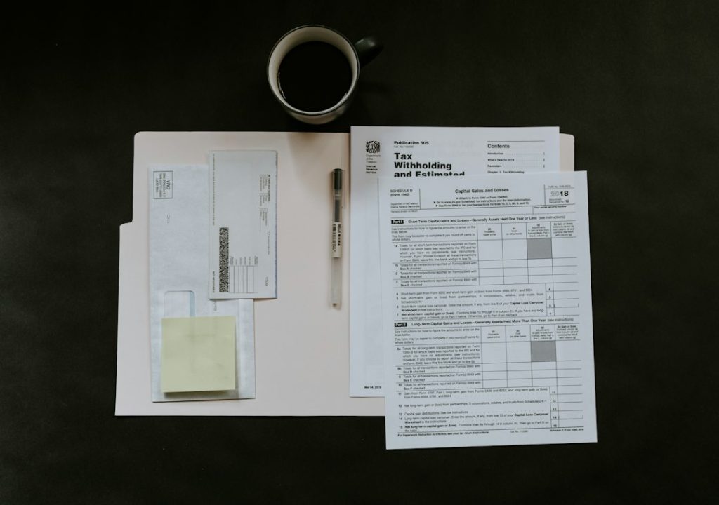 Tax forms, a pen, and a coffee mug on a dark desk